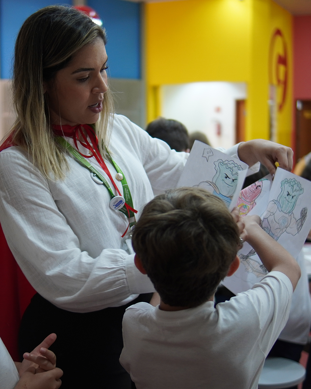 Nutricionista da Cancian vendo desenhos feitos por crianças em projeto Oficina Saudavel